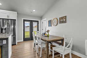 Dining room with french doors, light wood-style flooring, vaulted ceiling, and recessed lighting