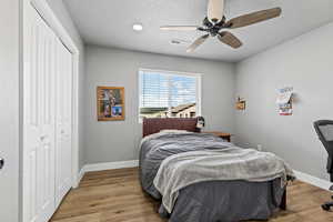 Bedroom with wood finished floors, a closet, and a ceiling fan