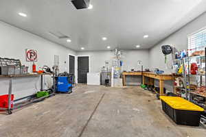 Garage with a workshop area, white fridge, secured water heater, a garage door opener, and electric panel