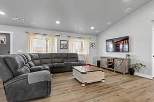 Living room with light wood finished floors, lofted ceiling, and recessed lighting