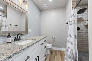 Full bath with a shower stall, vanity, and light wood-type flooring