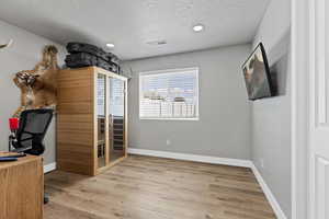 Office space featuring a sauna, light wood finished floors, a textured ceiling, and recessed lighting