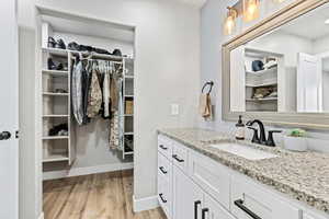 Bathroom featuring a spacious closet, vanity, and light wood finished floors