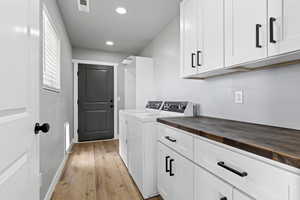 Laundry area with light wood-style flooring, independent washer and dryer, cabinet space, and recessed lighting