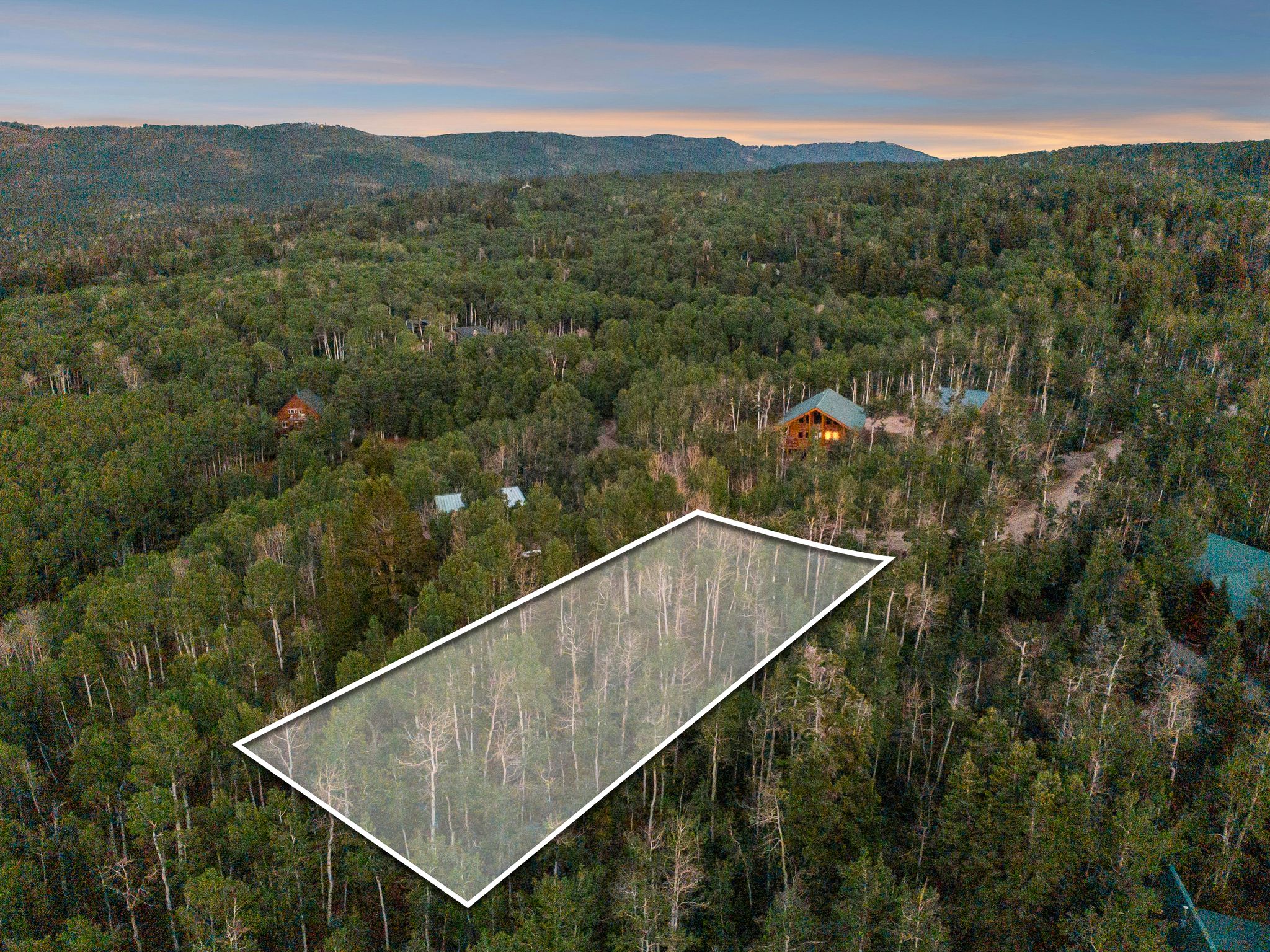 Aerial view at dusk of property boundaries highlighted, a view of trees, and a mountain view