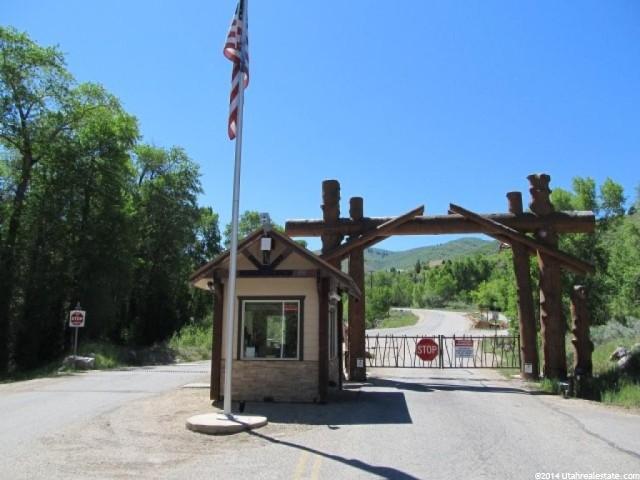 View of asphalt road with traffic signs, a gate, and a gated entry