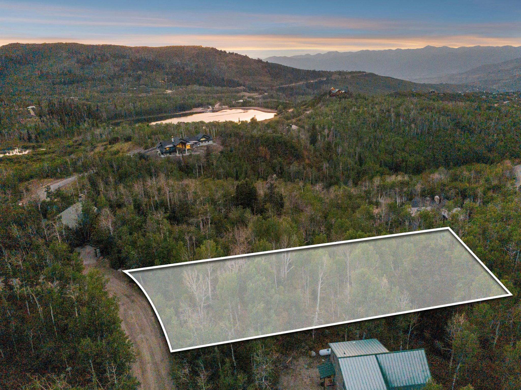 Aerial view at dusk of a mountain view, a wooded view, and property parcel outlined