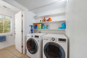 Laundry area with light tile patterned floors and washing machine and clothes dryer
