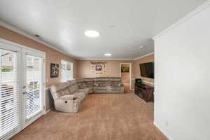 Living room with crown molding, light colored carpet, and french doors