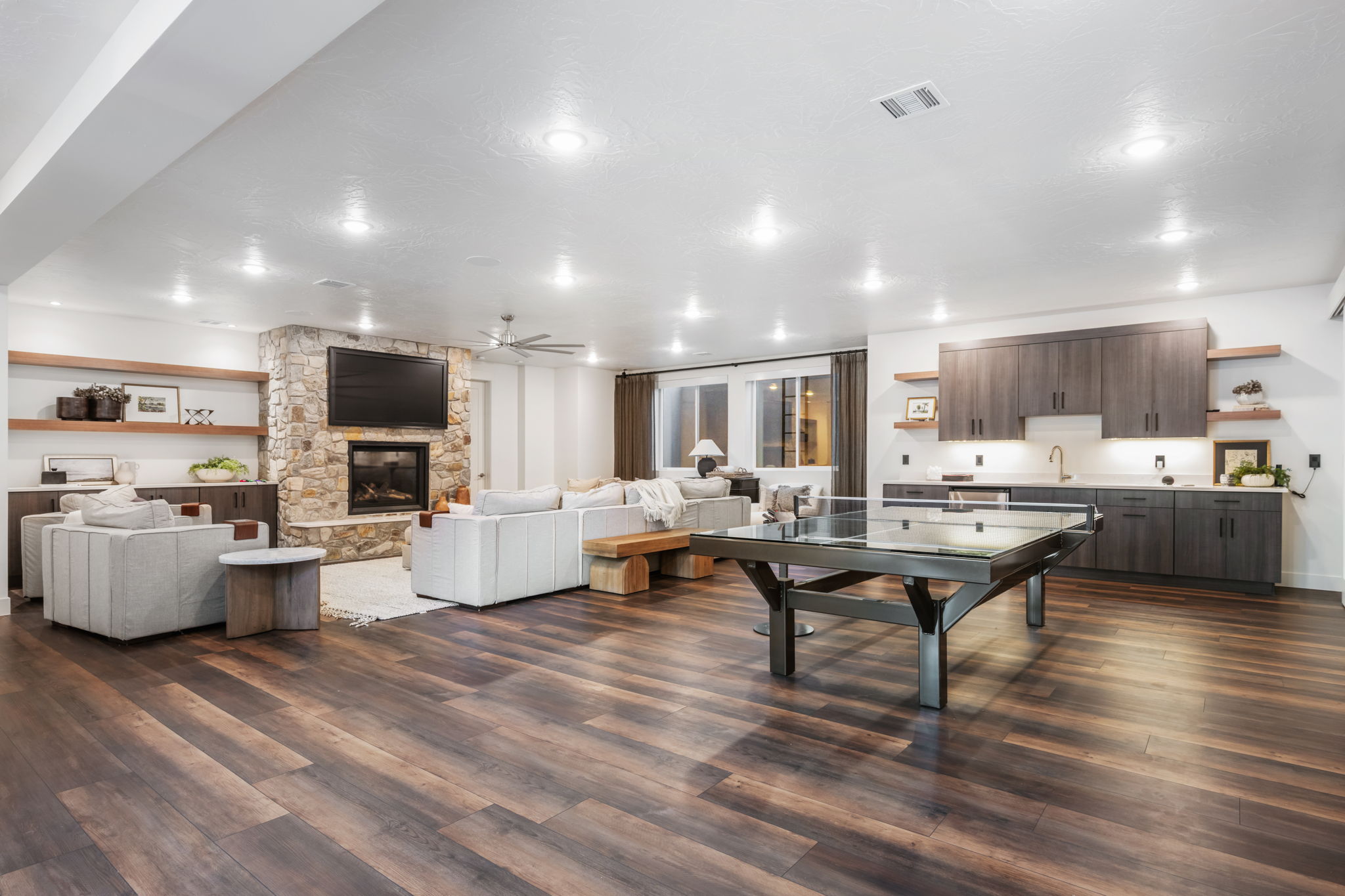 Living room featuring dark wood-style flooring, a ceiling fan, and a fireplace