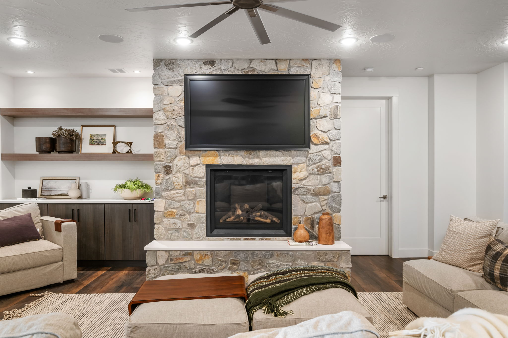 Living area with a ceiling fan, dark wood-style floors, a fireplace, and a textured ceiling