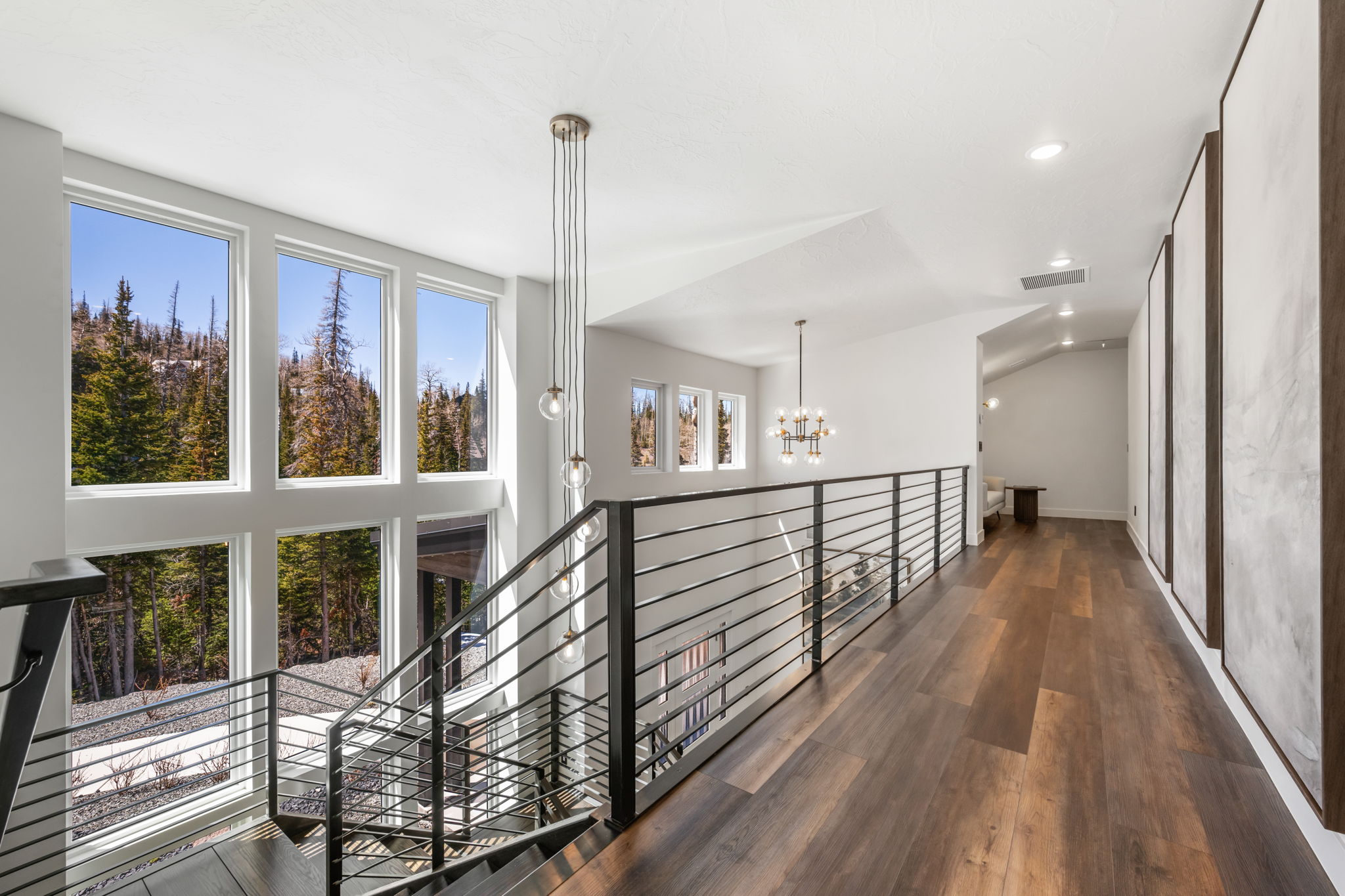 Hall featuring dark wood-type flooring, suspended lighting, an upstairs landing, and lofted ceiling