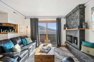 Living area with a mountain view, a large fireplace, and wood finished floors