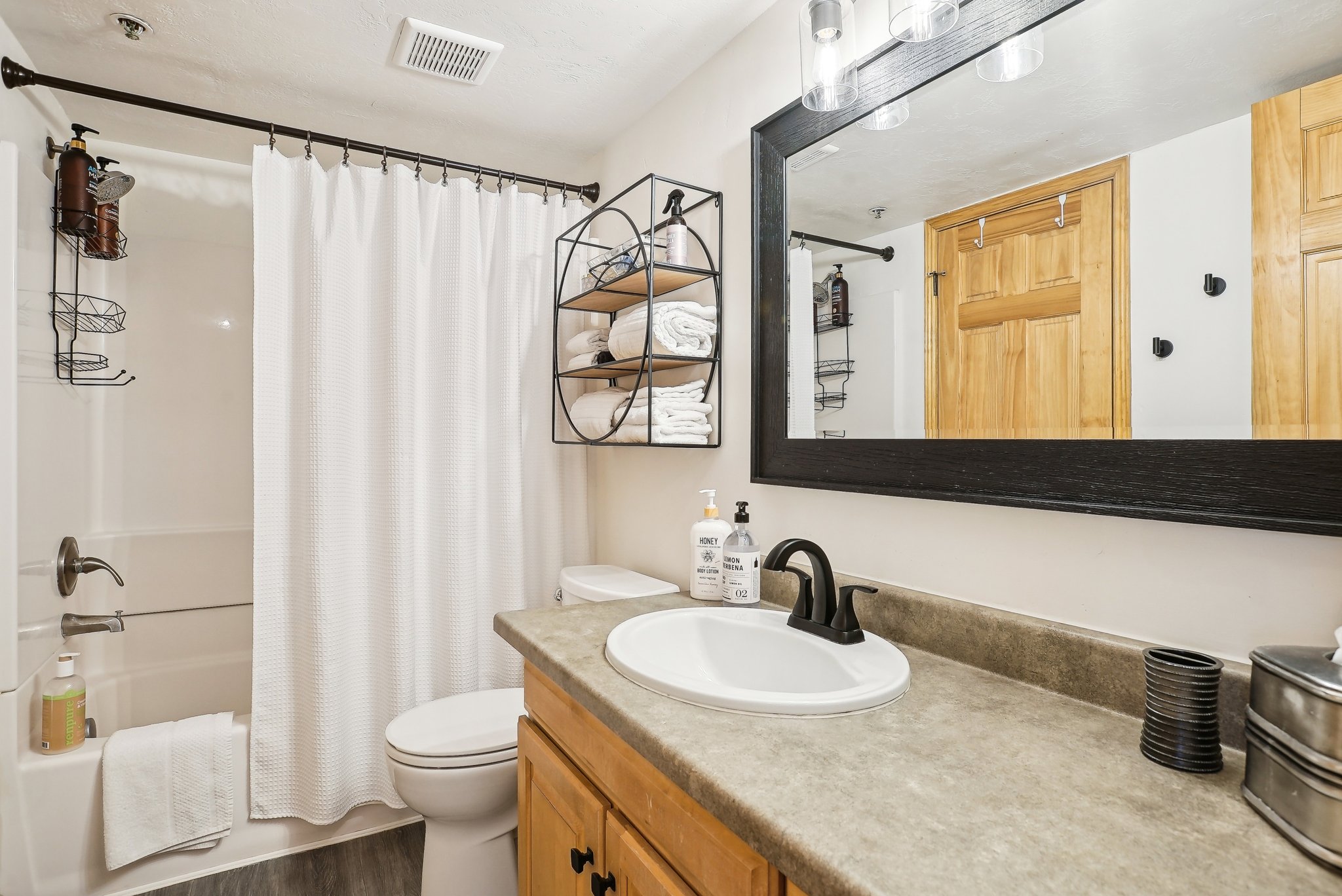 Full bathroom with vanity, shower / bath combination with curtain, and dark wood-type flooring