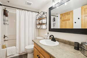 Full bathroom with vanity, shower / bath combination with curtain, and dark wood-type flooring