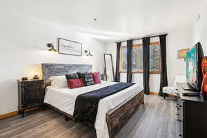 Bedroom with dark wood finished floors and baseboards