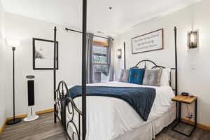 Bedroom with dark wood-style floors and baseboards