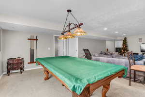 Game area featuring lighting for billiards table and textured ceiling