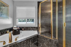 Marble primary bathroom with a stall shower and a jetted tub