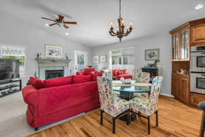 Dining space with a chandelier, hardwood flooring, a ceiling fan, a fireplace, and lofted ceiling
