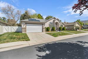 Single story home featuring solar panels, a gate, a front lawn, and concrete driveway