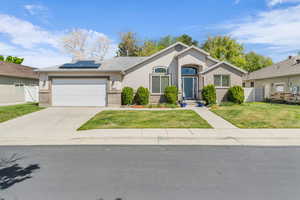 Single story home featuring roof mounted solar panels, brick and stucco siding, a 3-car garage, and concrete driveway