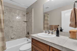 Bathroom featuring stone vanity and shower / bath combo