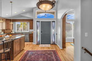 Foyer with light hardwood flooring, lofted ceiling, ample lighting, and arched walkways