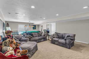 Carpeted basement living area featuring a textured ceiling, neutral colors and recessed lighting