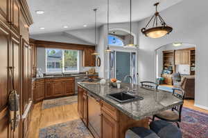 Kitchen with a kitchen breakfast bar, a center island with sink, slab granite countertops, vaulted ceiling, and Alder cabinets