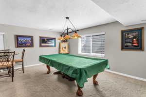 Game area with light carpet, a textured ceiling, and billiards table lighting