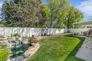 Fenced backyard with a patio area and a koi pond, koi and turtles included
