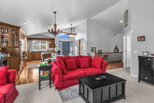 Living area with lofted ceiling, light carpet, suspended lighting, and arched walkways