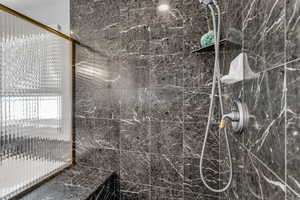 Primary shower featuring a marble finish and custom seat