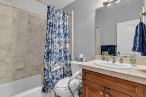 Full bath featuring stone vanity and shower / bath combination