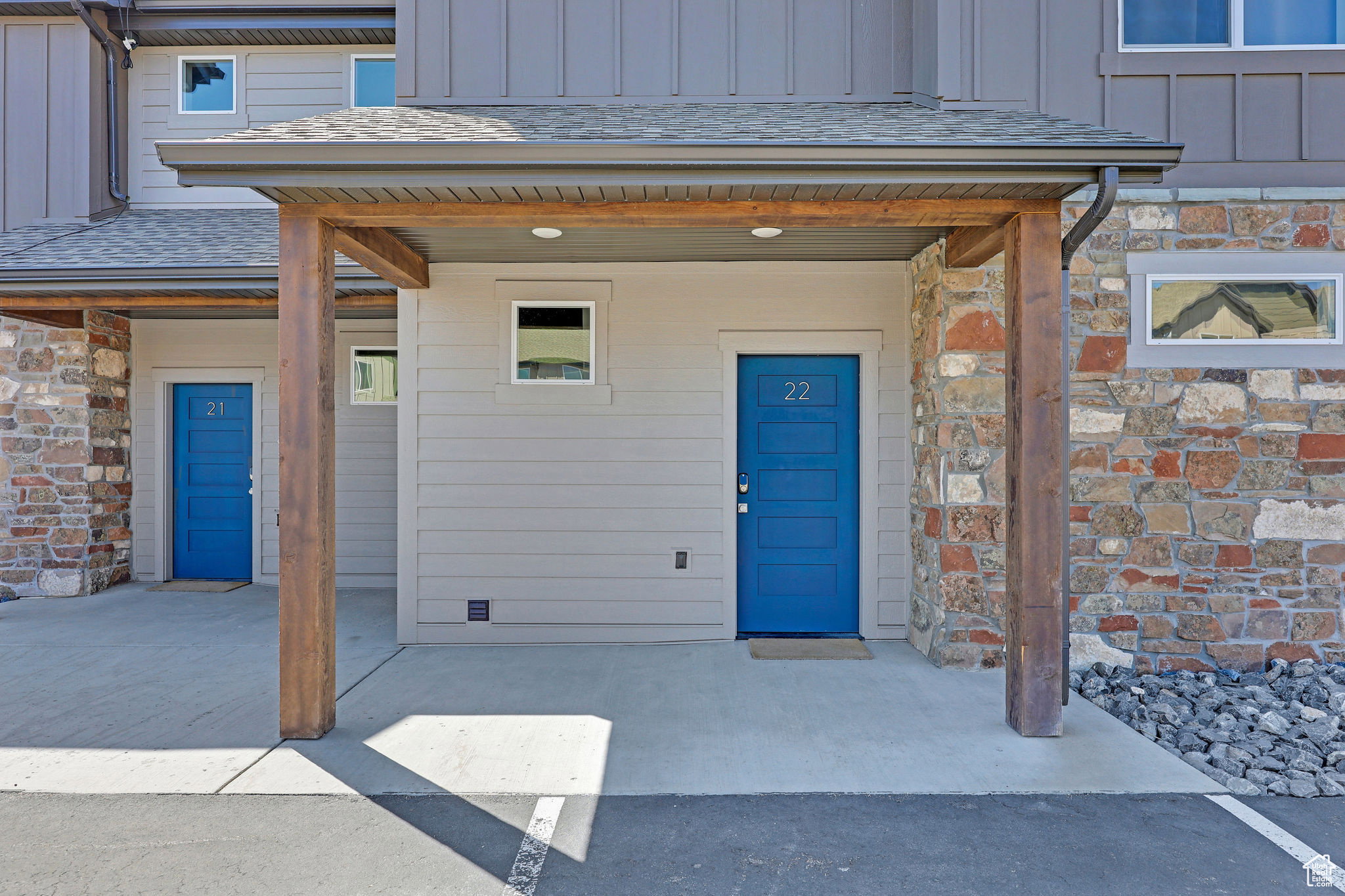 Property entrance featuring board and batten siding, stone siding, a shingled roof, and a porch