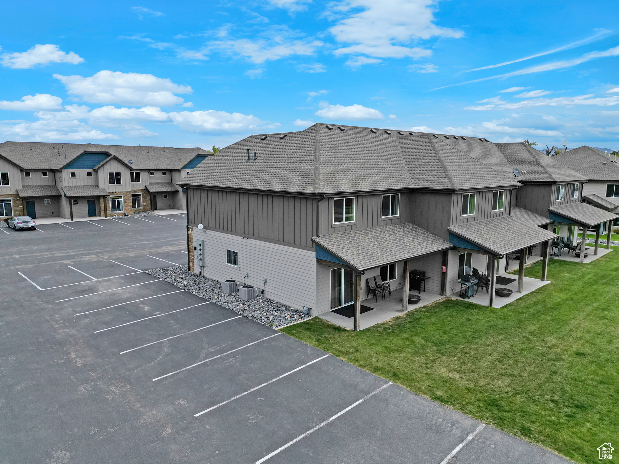 Back of house featuring uncovered parking, roof with shingles, a residential view, and a yard