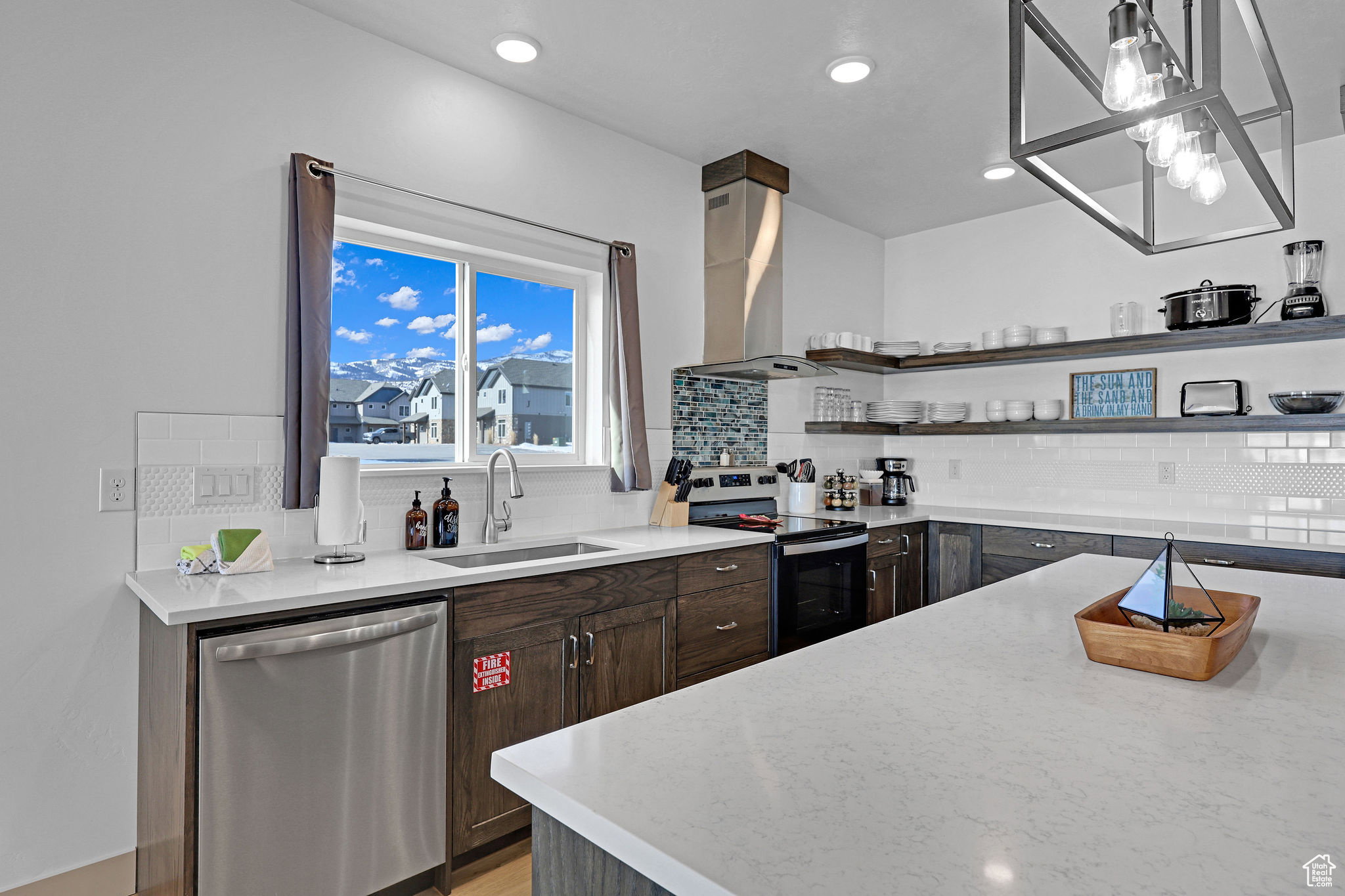 Kitchen with dishwasher, electric range oven, light stone countertops, exhaust hood, and dark wood finish cabinets