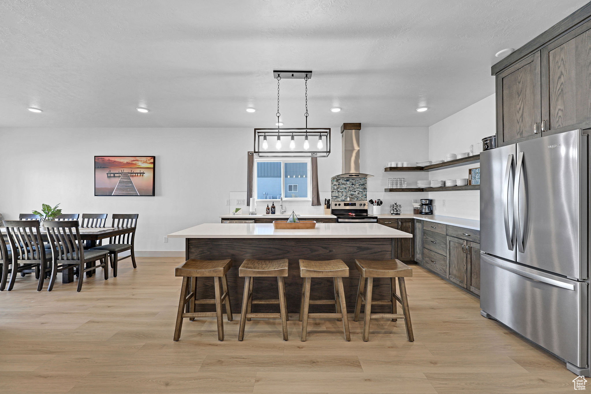 Kitchen featuring stainless steel appliances, light wood-style floors, a breakfast bar, a kitchen island, and pendant lighting