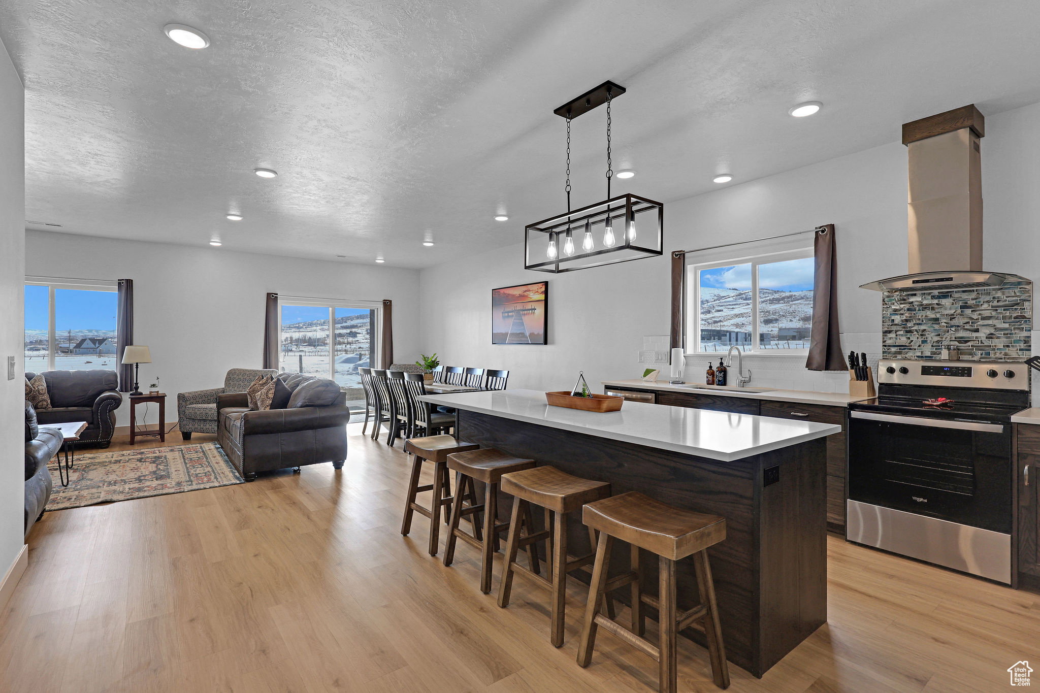 Kitchen with electric stove, a breakfast bar, backsplash, island range hood, and a kitchen island