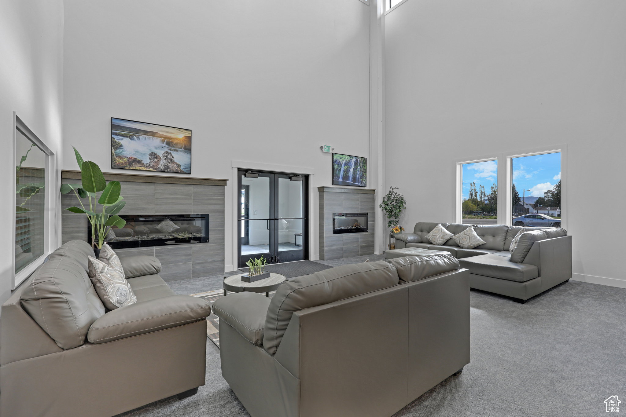 Carpeted living room featuring a tiled fireplace and a high ceiling