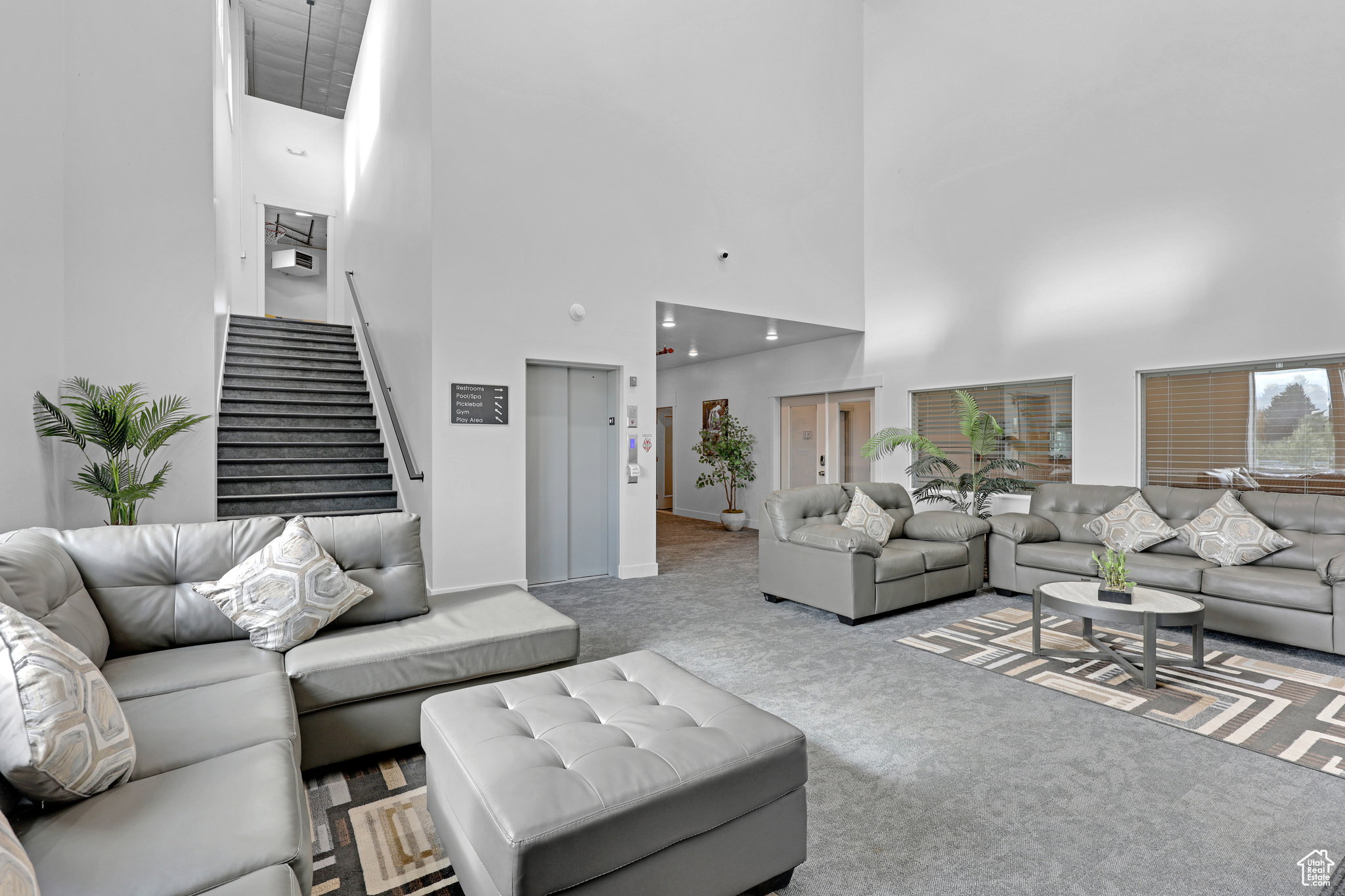 Carpeted living area with elevator and a high ceiling