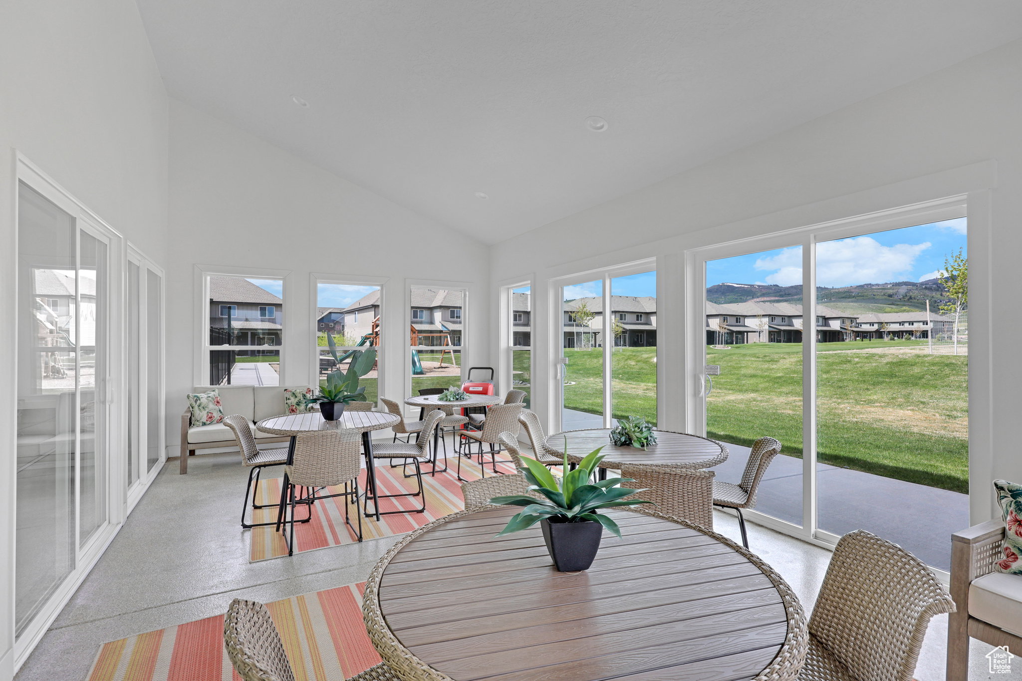 Sunroom featuring speckle patterned floor, lofted ceiling, healthy amount of natural light, and a residential view