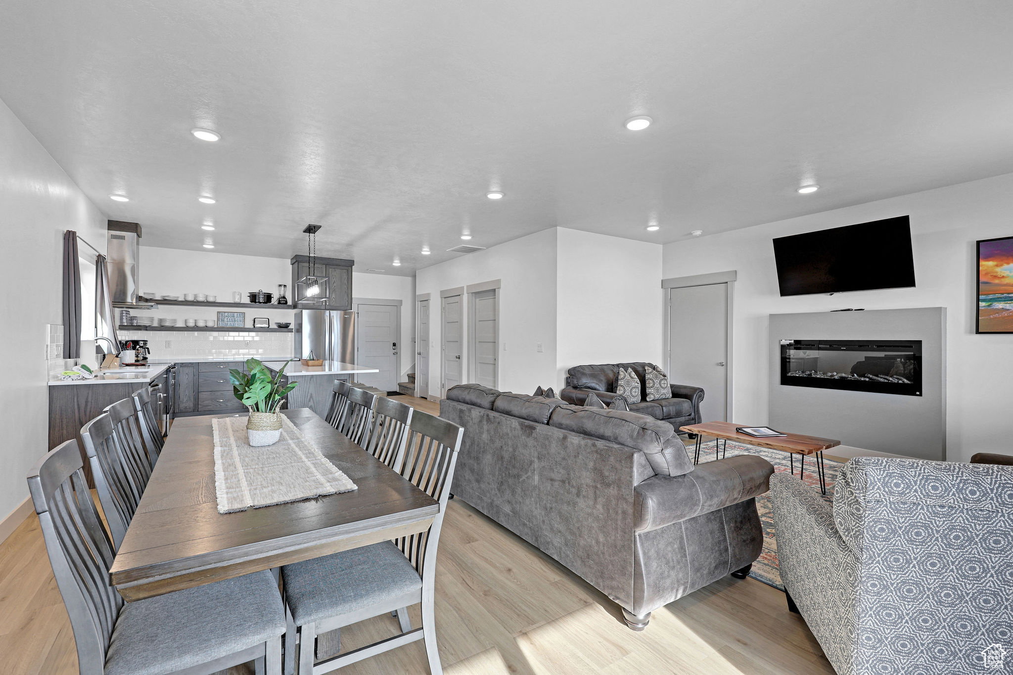 Dining room featuring light wood-style floors, a glass covered fireplace, and recessed lighting