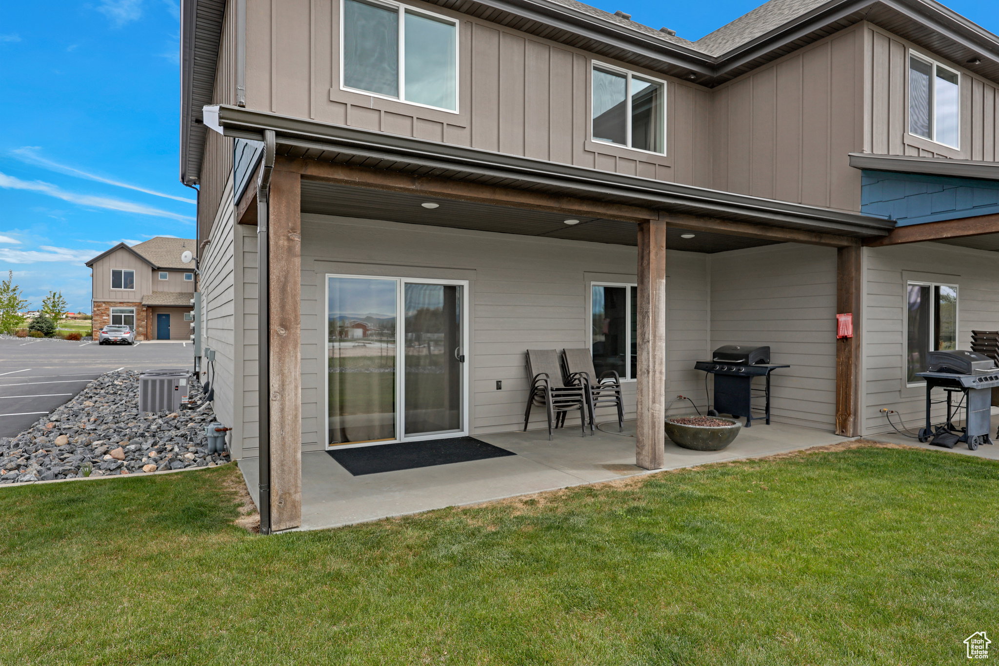 Rear view of property with board and batten siding, a lawn, and a patio area