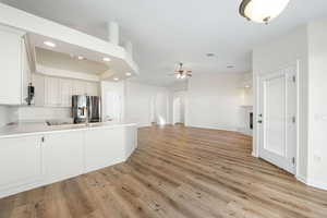 Kitchen with stainless steel fridge with ice dispenser, lofted ceiling, arched walkways, light wood finished floors, and a peninsula