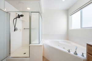Bathroom featuring a shower stall, vanity, a jetted tub, and recessed lighting