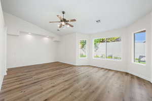 Unfurnished room with a ceiling fan, light wood-type flooring, and lofted ceiling