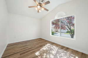 Empty room with light wood-type flooring, vaulted ceiling, and a ceiling fan
