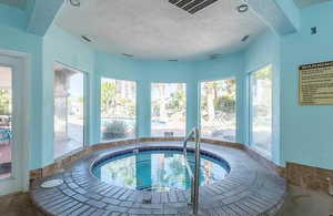 View of pool with a hot tub and a sunroom